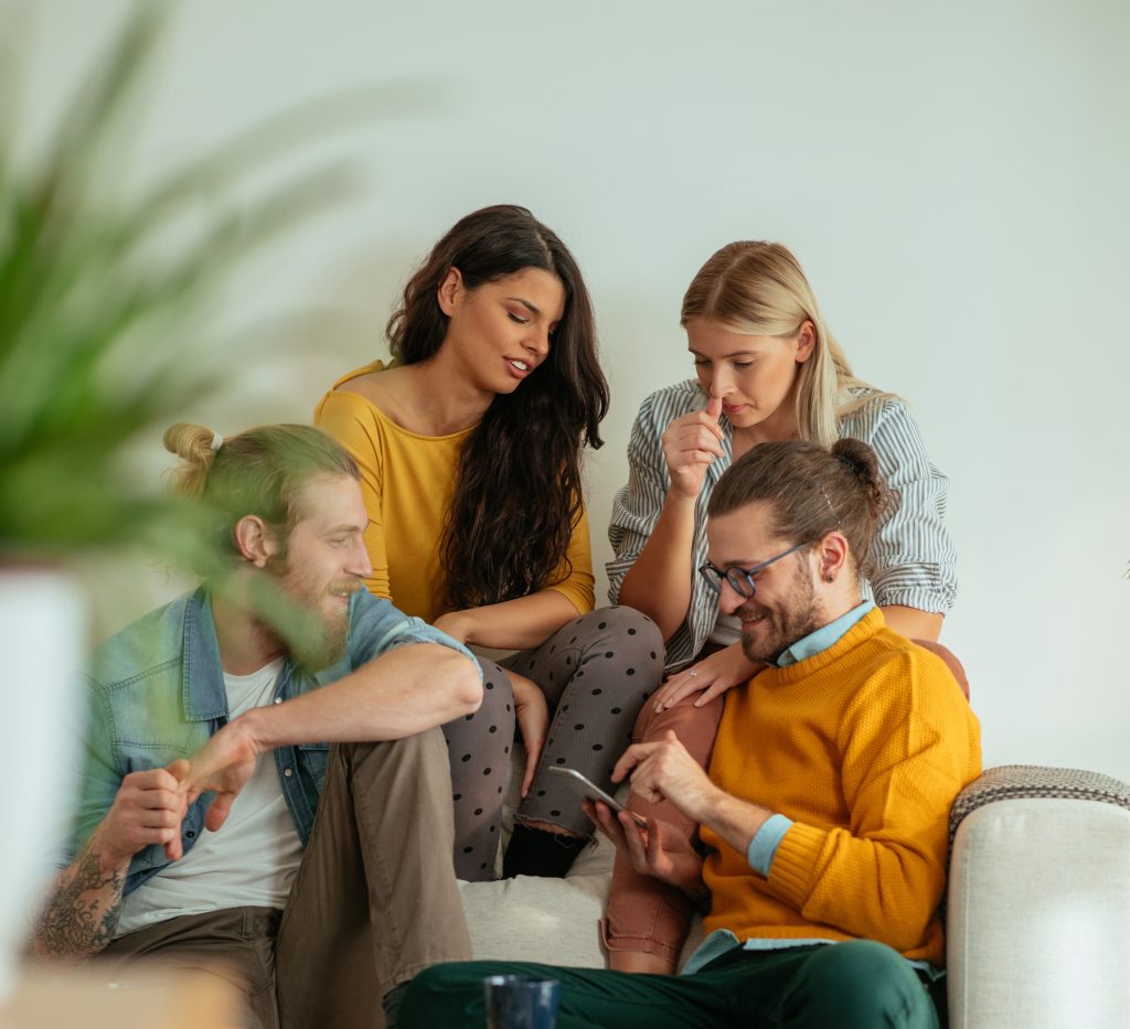 Groep jonge vrienden zit op de bank in de woonkamer en gebruiken WhatsApp in klantcontact