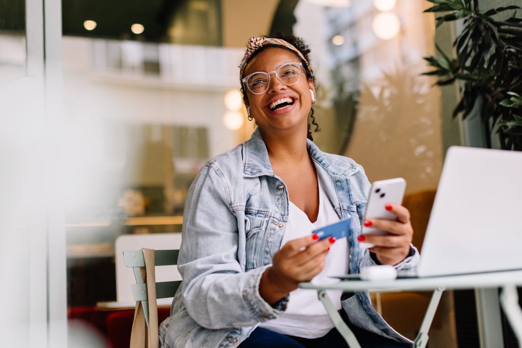 smiling woman with a phone and bank card at her desk in an inbound call center